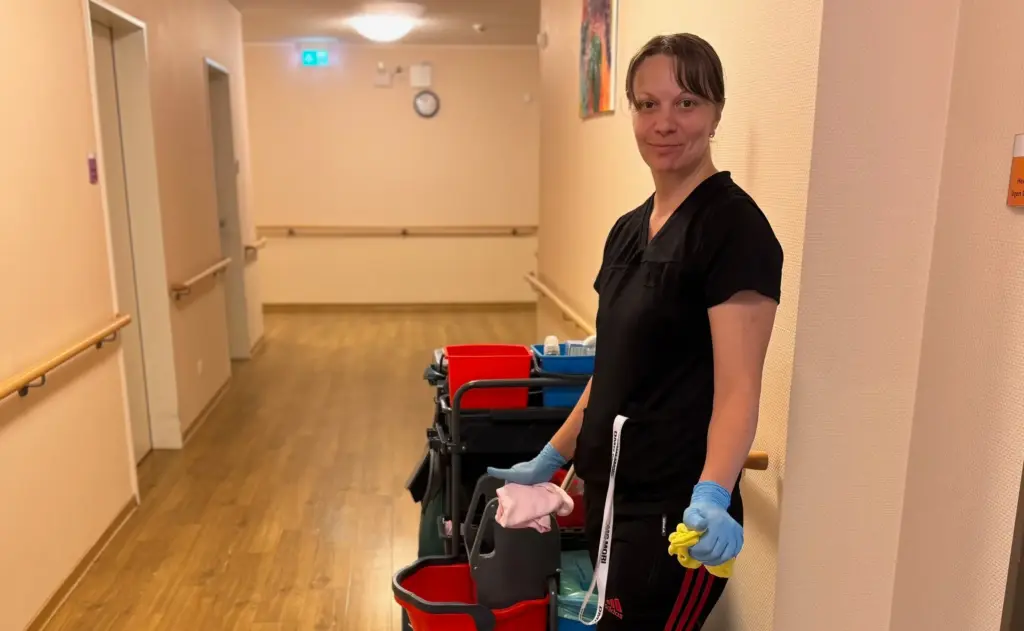 Reinigungskraft im Haus Tannenberg Gummersbach steht mit Putzwagen und Reinigungsutensilien in einem Flur des Gebäudes.
